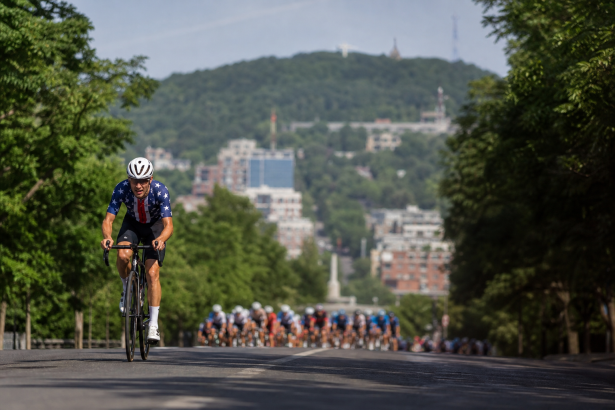 Ciclista em prova de estrada em Montreal com pelotão ao fundo