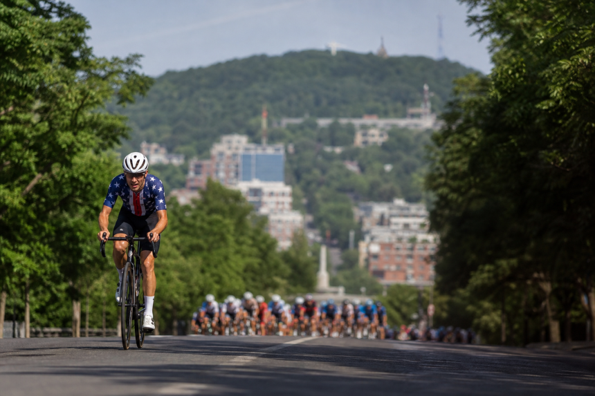 Ciclista em prova de estrada em Montreal com pelotão ao fundo