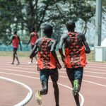 Dois atletas correm lado a lado em uma pista de atletismo em Nairóbi, no Quênia.
