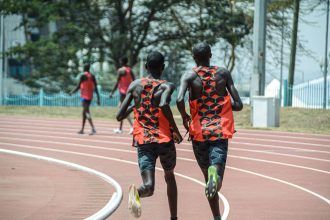 Dois atletas correm lado a lado em uma pista de atletismo em Nairóbi, no Quênia.
