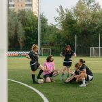 Grupo de adultos reunido para uma conversa em um campo de futebol ao ar livre.