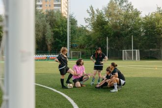 Grupo de adultos reunido para uma conversa em um campo de futebol ao ar livre.