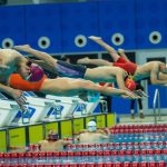 Nadadores mergulham simultaneamente na piscina durante a largada de uma competição.