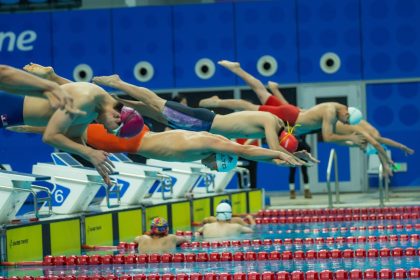 Nadadores mergulham simultaneamente na piscina durante a largada de uma competição.