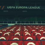 Arquibancadas vazias de um estádio esportivo decoradas com faixas da UEFA.