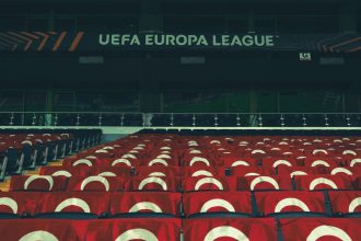 Arquibancadas vazias de um estádio esportivo decoradas com faixas da UEFA.
