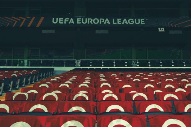 Arquibancadas vazias de um estádio esportivo decoradas com faixas da UEFA.