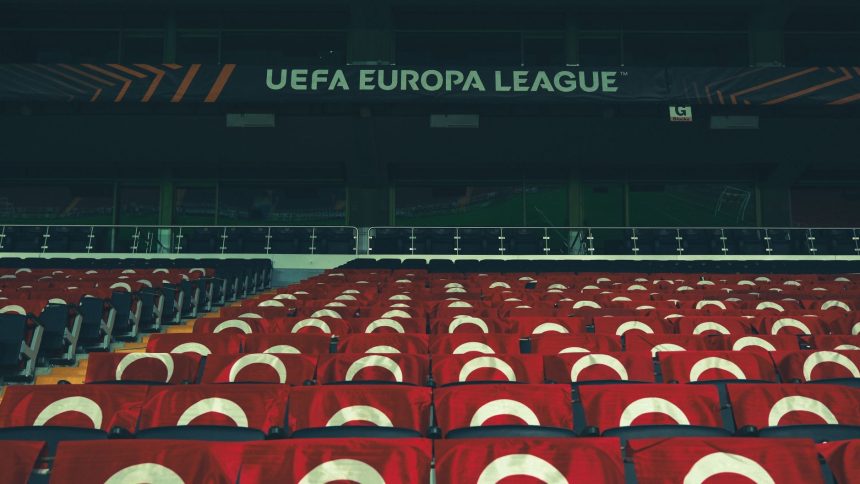 Arquibancadas vazias de um estádio esportivo decoradas com faixas da UEFA.