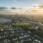 Vista aérea de Brisbane ao pôr do sol, com o rio e o horizonte urbano da cidade australiana.