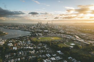 Vista aérea de Brisbane ao pôr do sol, com o rio e o horizonte urbano da cidade australiana.