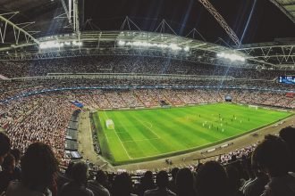 Arquibancadas de um estádio de futebol lotadas de torcedores durante uma partida.